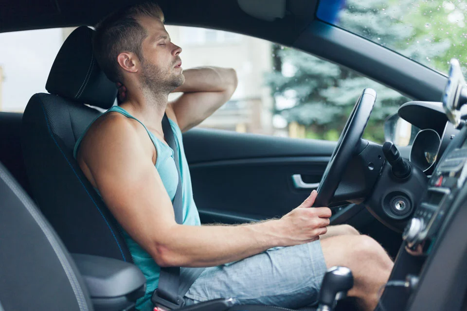 driving man experiencing neck pain and is in need of a whiplash treatment